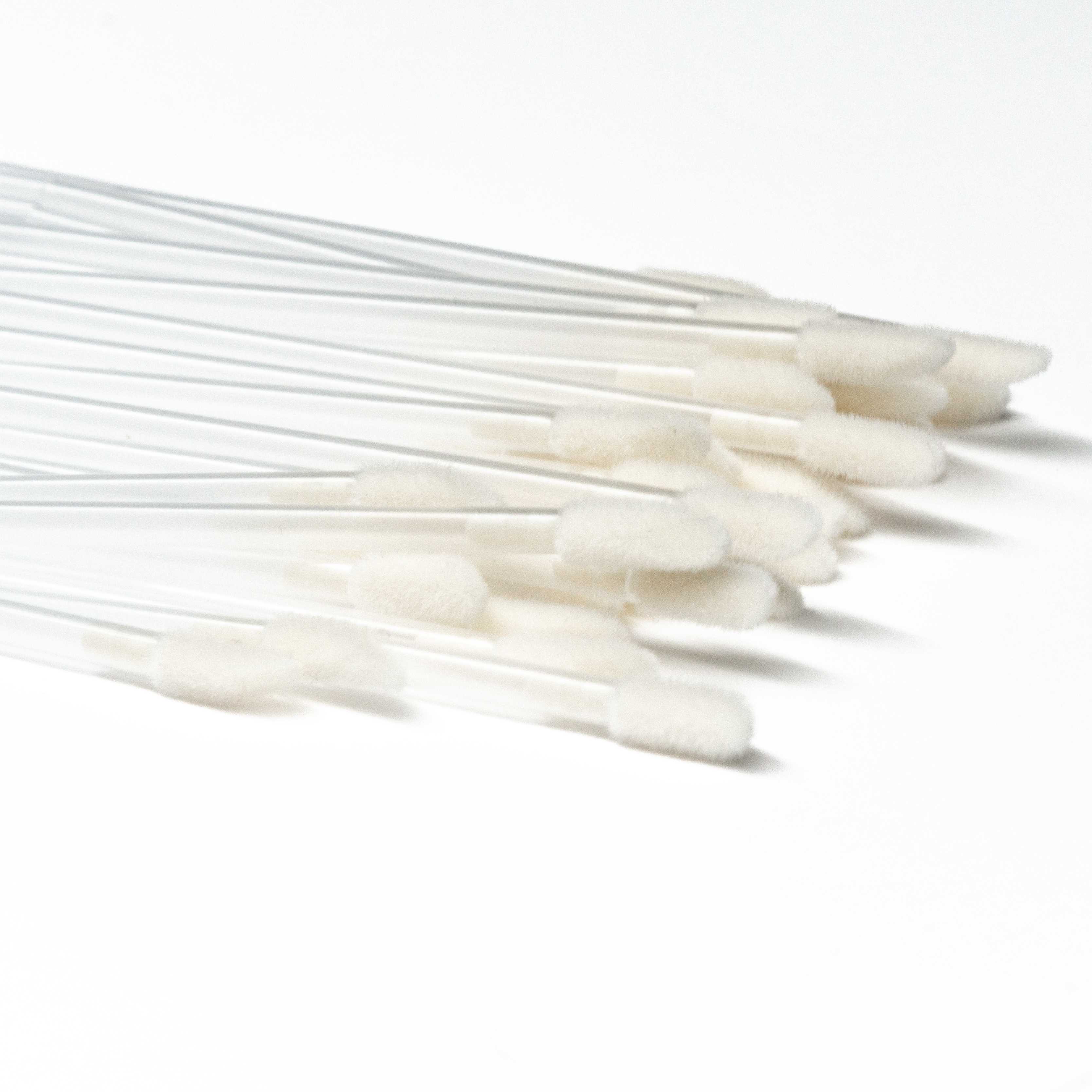A pile of 50 disposable applicator wands on a white background