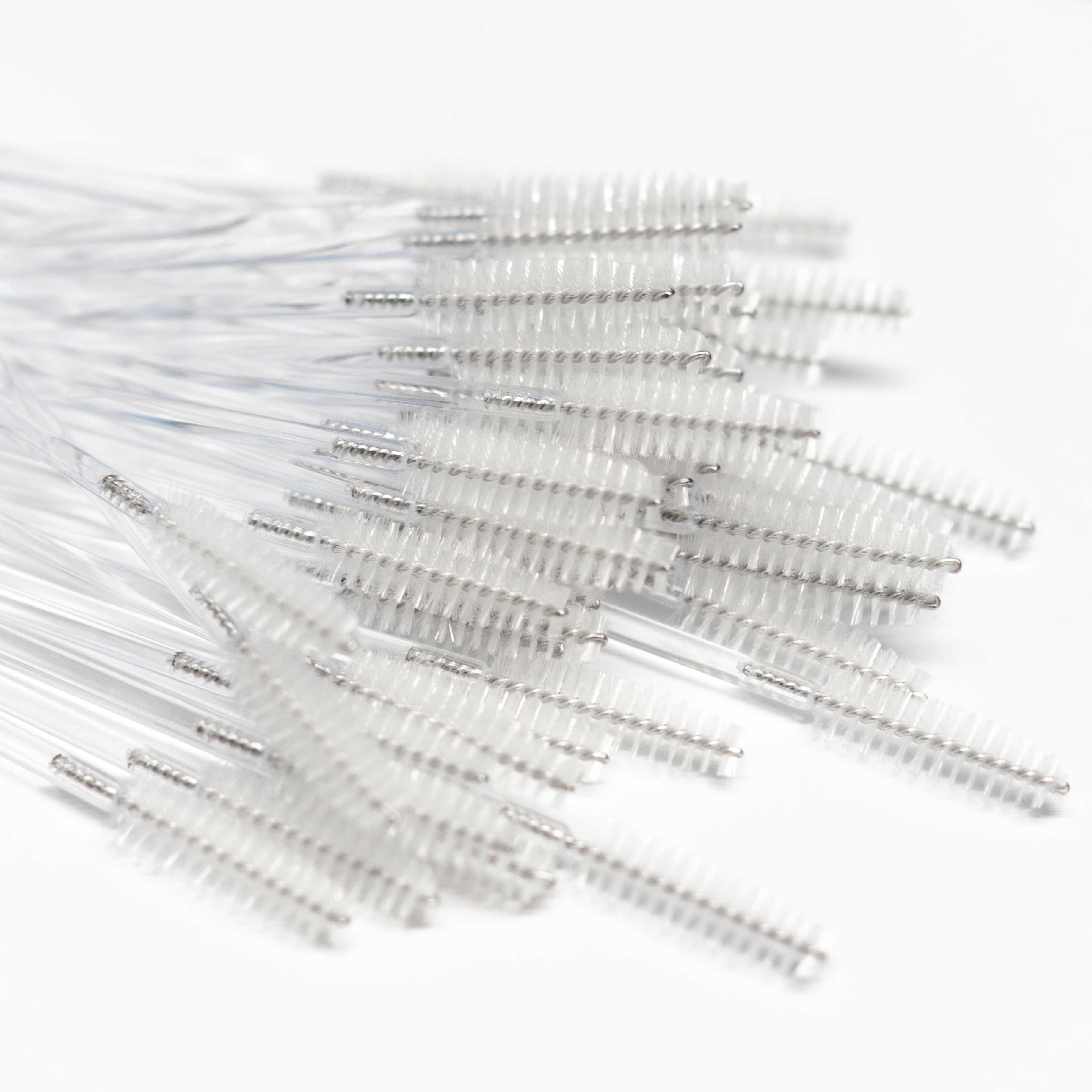 A pile of 50 mascara brushes on a white background