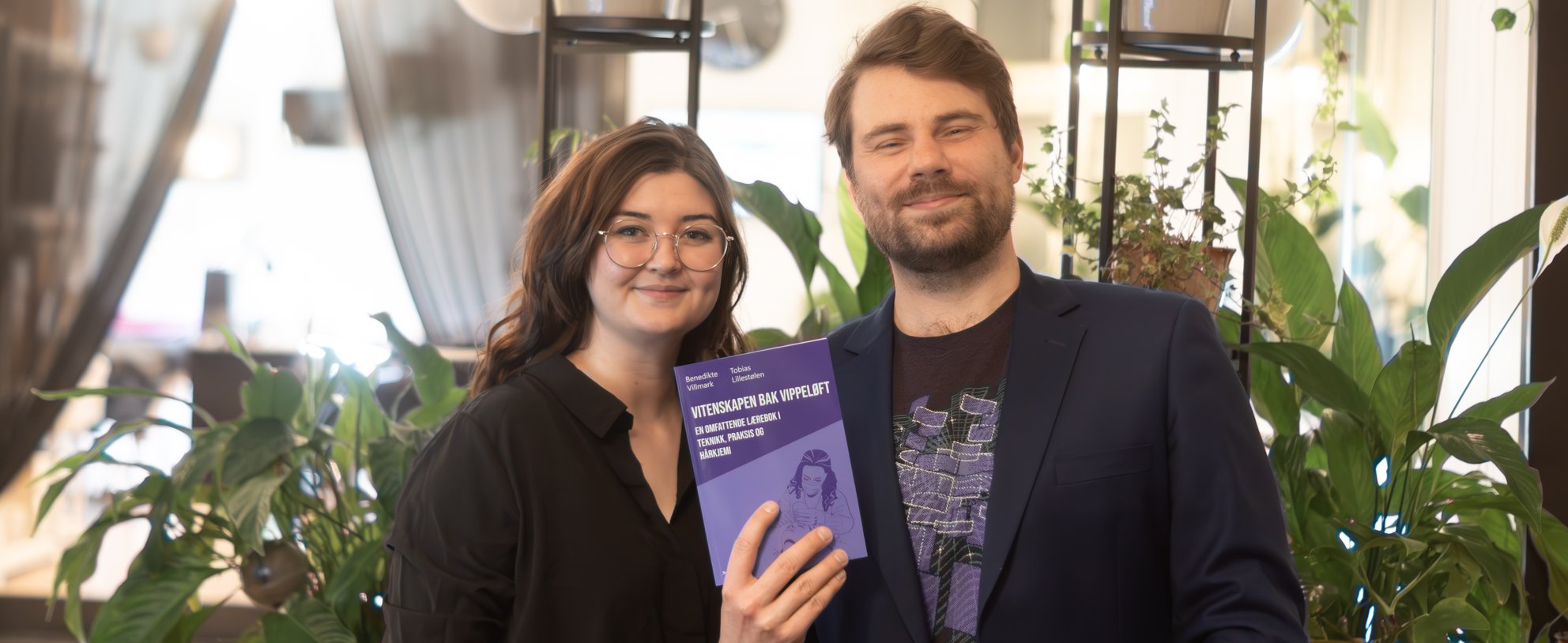 Benedikte Villmark and Tobias Lillestølen holding the book "Vitenskapen bak vippeloft"